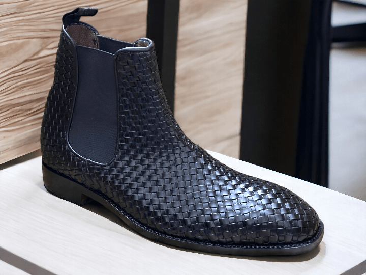 Expertly crafted and stylish, these black woven leather Chelsea boots are the perfect addition to any man's wardrobe. With a sleek and fashionable design, these boots will elevate any outfit while providing comfort and durability. Perfect for any dressy occasion, these handmade boots are a must-have for the modern man.